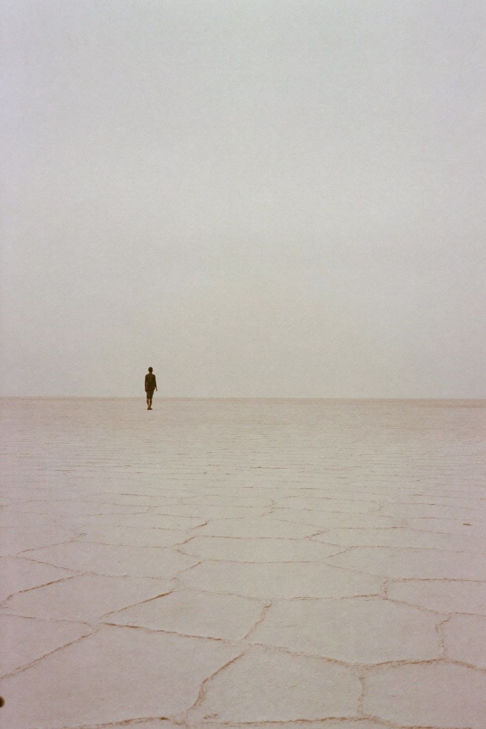 Distant figure crossing a bleached salt flat